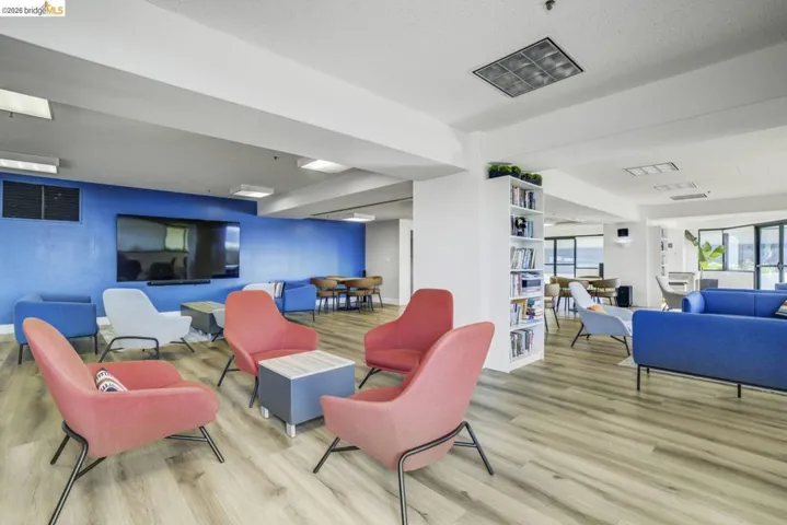 Spacious common area featuring wood-finish flooring, a large wall-mounted television, and built-in shelving