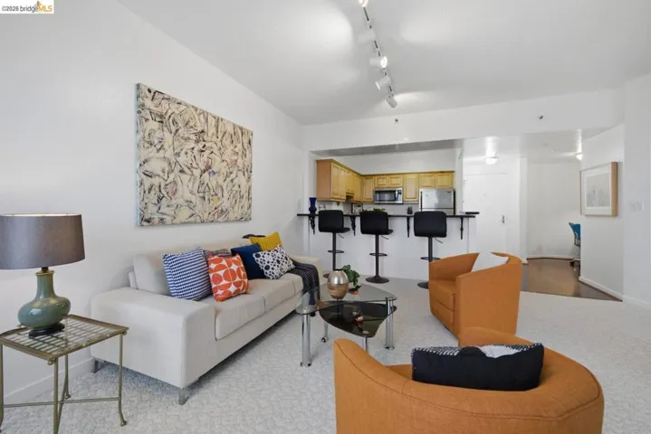 Open-concept living area with light-colored carpet flooring and track lighting