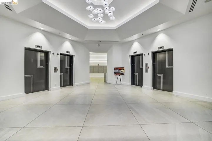 Spacious lobby featuring multiple elevators with decorative paneling and a modern chandelier