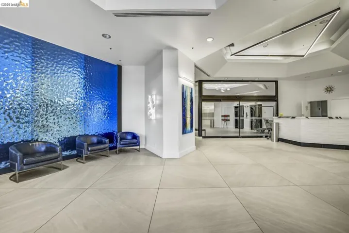 Lobby area featuring an accent wall with textured blue panels, large format tile flooring, a geometric ceiling light fixture, and a reception desk