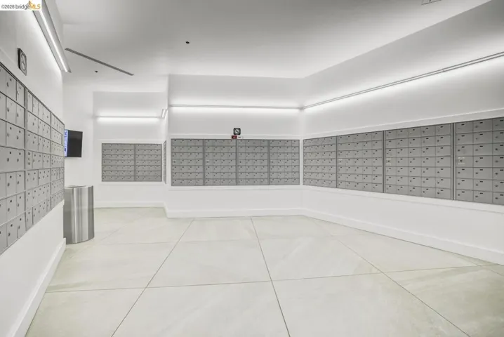 Mailroom featuring multiple banks of individual mailboxes, light-toned large format floor tiles, and recessed strip lighting