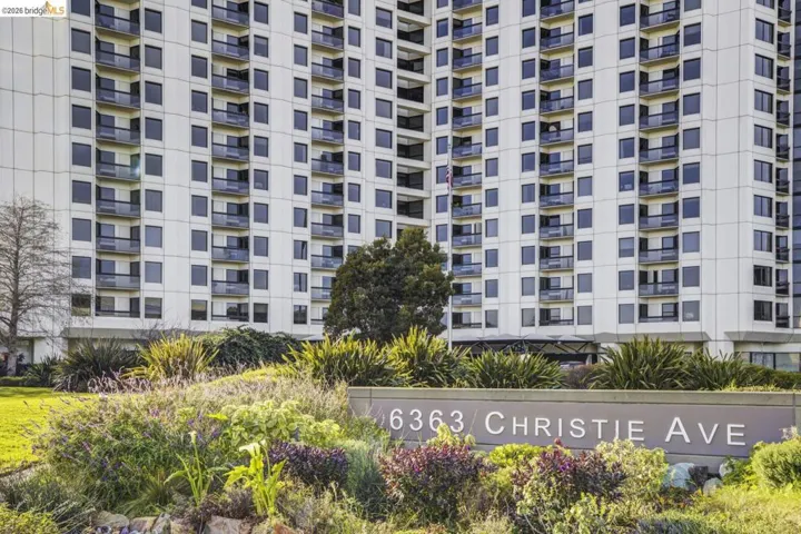 High-rise building with a light-colored facade and numerous balconies featuring dark railings