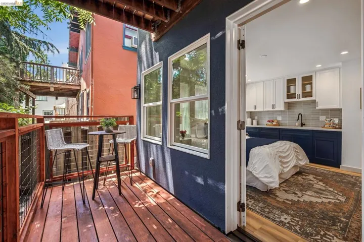 Private balcony featuring wood-finish flooring and metal railing, with an exterior wall sconce