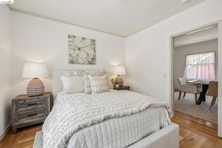 Light-filled interior featuring wood-finish flooring, white walls, and a doorway leading to an additional space