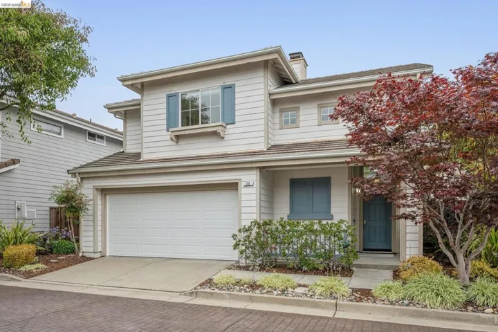 Two-story residence featuring light-toned siding, a two-car garage, and blue window shutters