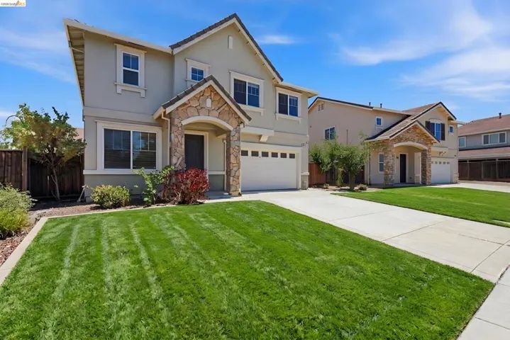 Two-story stucco exterior featuring stone accents and a covered front entry