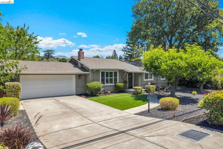 Ranch-style residence featuring a gray exterior, a two-car garage, and a concrete driveway