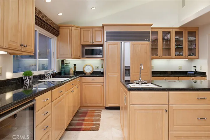Beautifully Remodeled Kitchen Offers an Island with Prep Sink, Sub-Zero Fridge, Cabinets with Glass Door for Display.