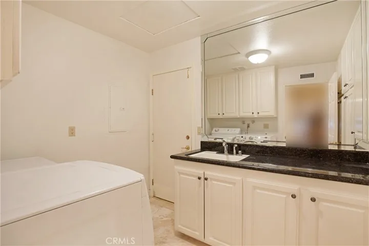 Private Laundry Room Offers Granite Counter Top and a Sink.