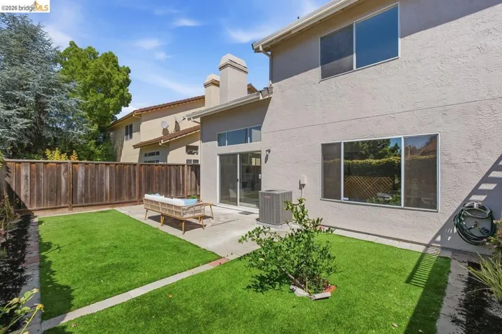Private backyard featuring a concrete patio, artificial turf, and a wood privacy fence