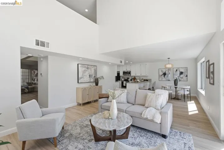 Open-concept living space featuring high ceilings, wood-finish flooring, recessed lighting, and ample natural light from multiple windows