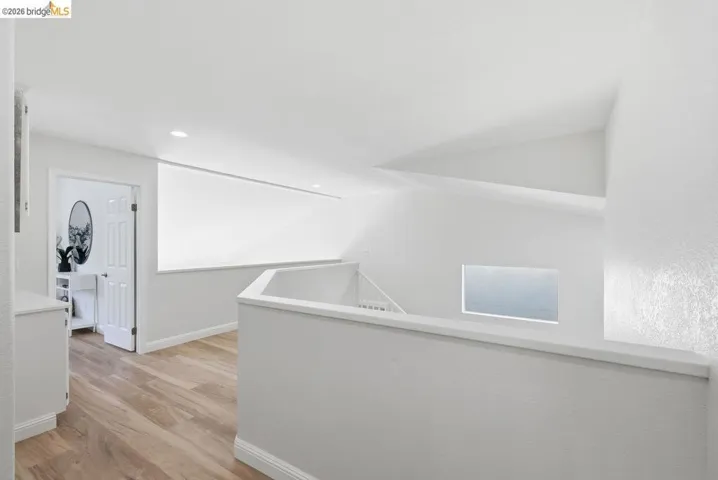 Open landing area featuring light wood-finish flooring and white painted walls