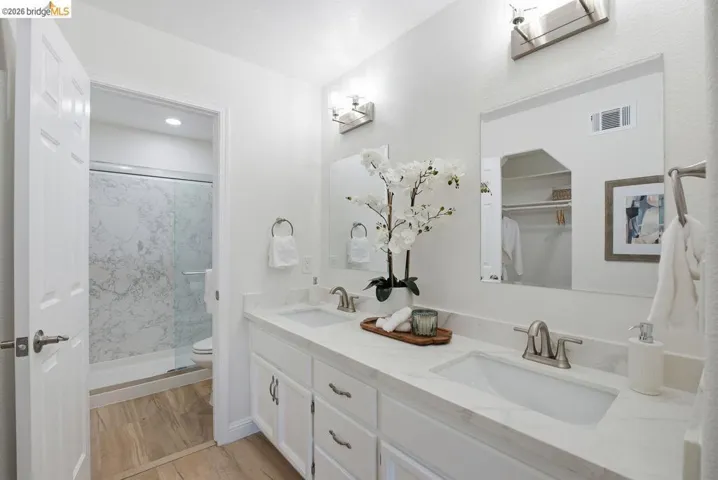 Dual vanity with white cabinetry, integrated sinks, brushed nickel fixtures, and light-toned countertops