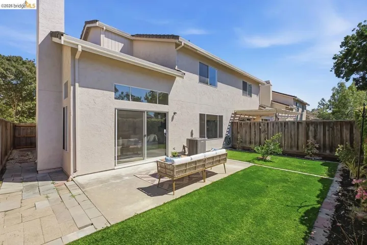 Expansive backyard featuring a lush lawn, concrete patio, and a stone paver walkway