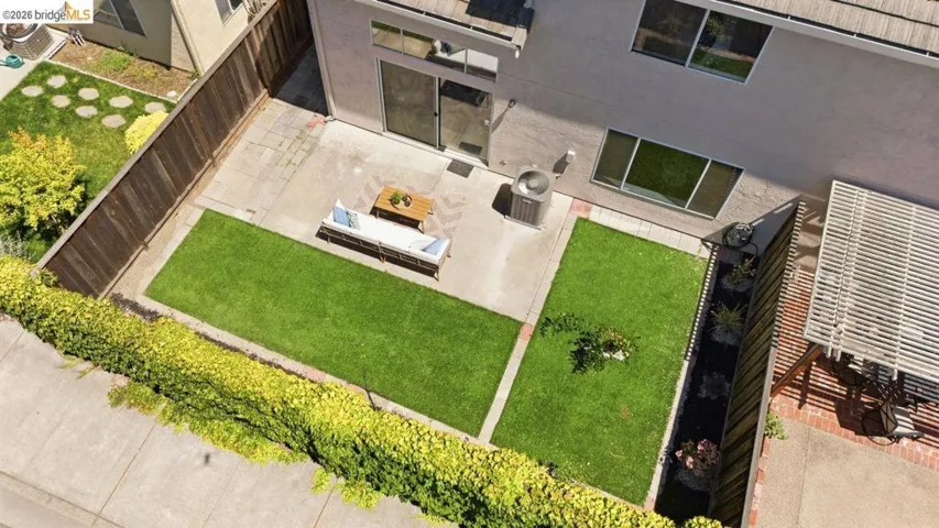 Private backyard featuring a concrete patio, two distinct lawn areas, and perimeter fencing