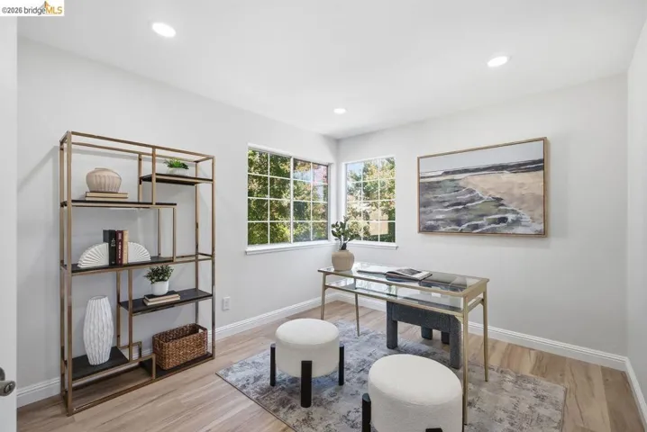 Light-filled room featuring two windows, wood-finish flooring, recessed lighting, and white baseboards