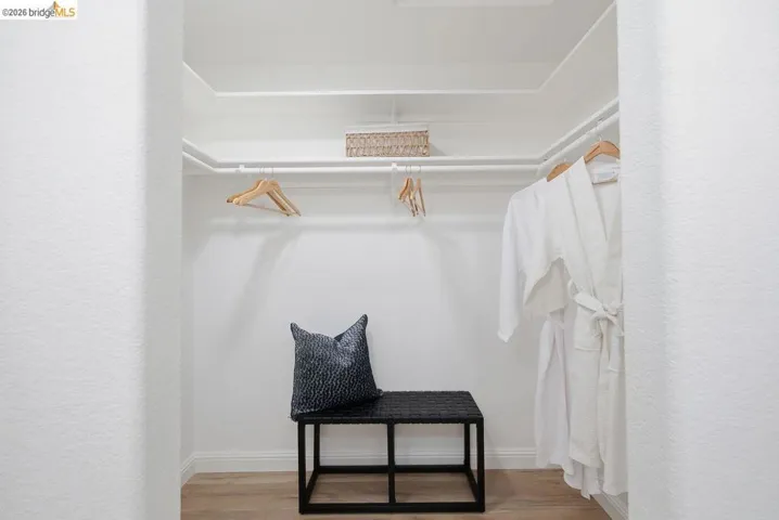 Walk-in closet featuring white shelving, white hanging rods, and light wood-finish flooring