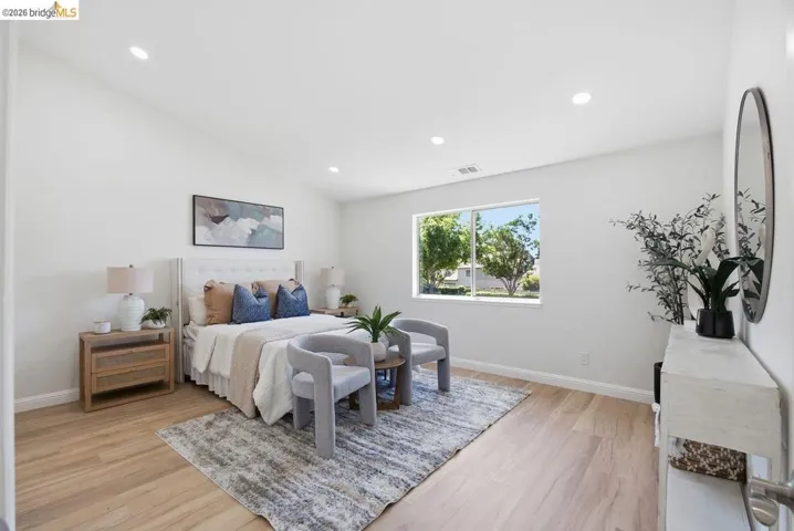 Spacious room featuring light wood-finish flooring, recessed lighting, and a large window