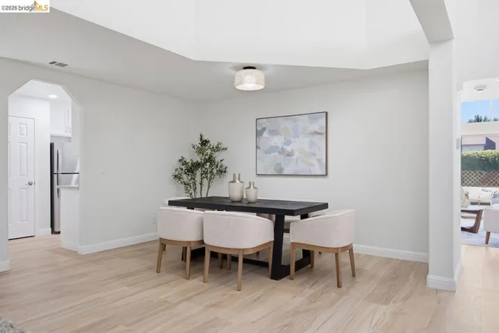 Spacious dining area featuring light wood-finish flooring and a contemporary overhead light fixture