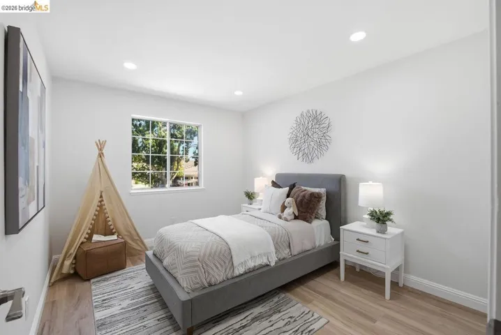 Bedroom featuring wood-finish flooring, recessed lighting, and a window with grid panes