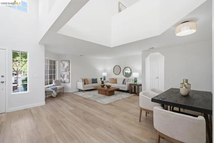 Spacious living area featuring high ceilings, wood-finish flooring, abundant natural light from large windows, and an open layout