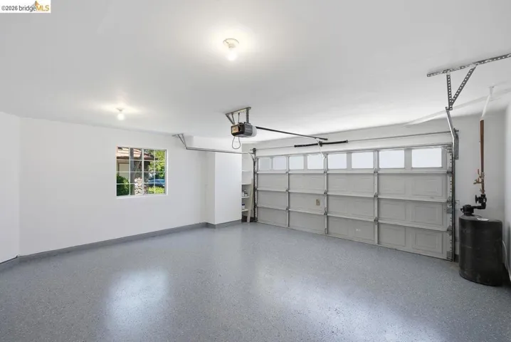 Spacious garage with light grey epoxy flooring, white walls, and two ceiling-mounted light fixtures