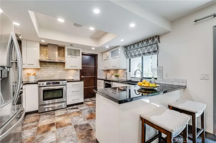 Beautifully Remodeled Kitchen with Tray Ceiling, Stone Flooring, and Breakfast Bar