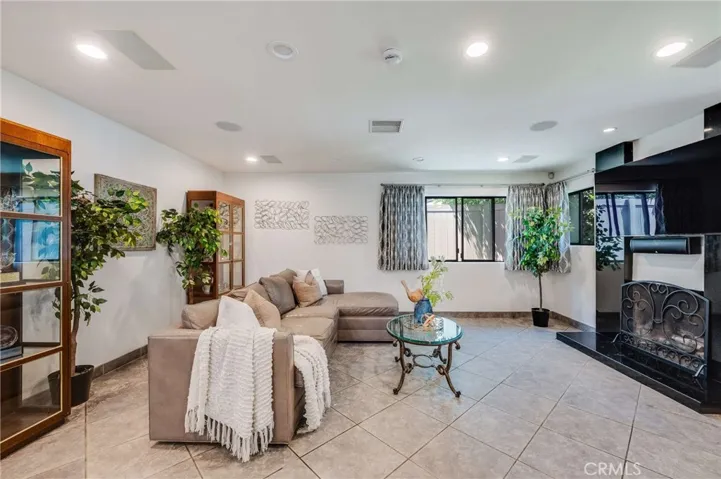 Beautiful Step Down Living Room with Recessed Lighting, Tiled Floors, and Black Granite Fireplace and Hearth