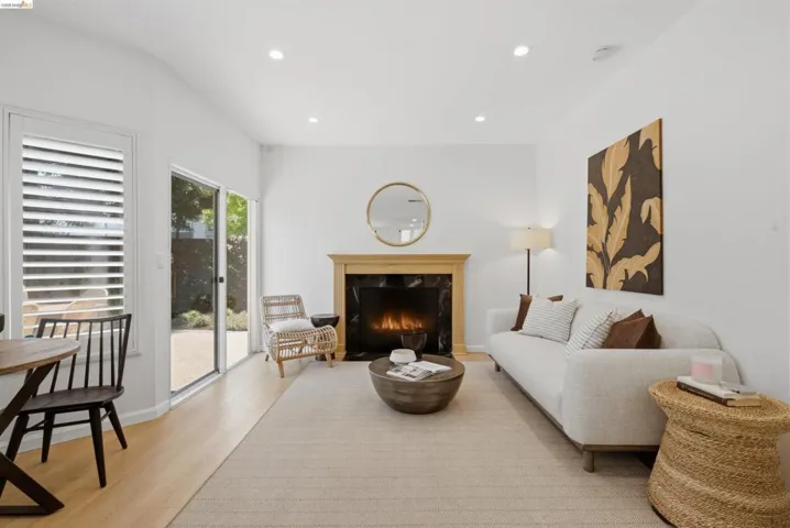 Living area featuring a fireplace with a wood mantle and dark stone surround, recessed lighting, wood-finish flooring, and a sliding glass door leading to an outdoor space