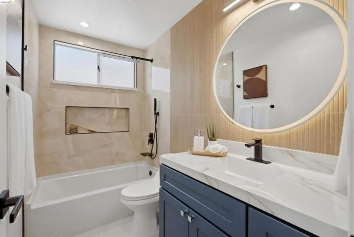 Bathroom featuring a white bathtub, a wall-mounted shower system with a handheld sprayer, and a recessed niche