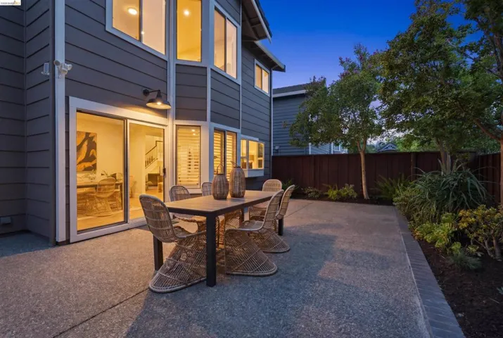 Spacious concrete patio featuring a modern exterior light fixture