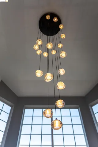 Multi-tiered chandelier featuring numerous clear glass orbs suspended from a black ceiling plate