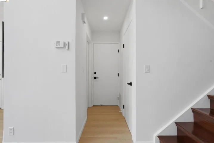 Entryway featuring light wood-finish flooring, white walls, recessed lighting, and a dark wood staircase