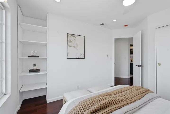 Recessed lighting throughout, dark wood-finish flooring, built-in shelving, white ceiling fan, and white walls