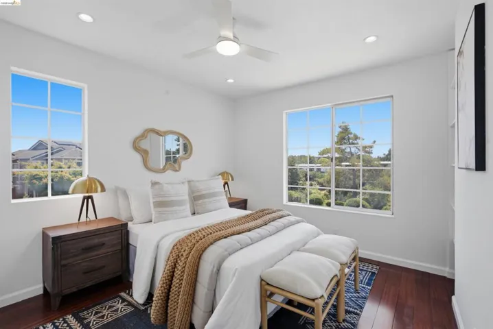 Bright bedroom featuring two large windows with grid panes, recessed lighting, a ceiling fan, and wood-finish flooring