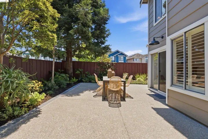 Expansive concrete patio bordered by mature trees and varied landscaping