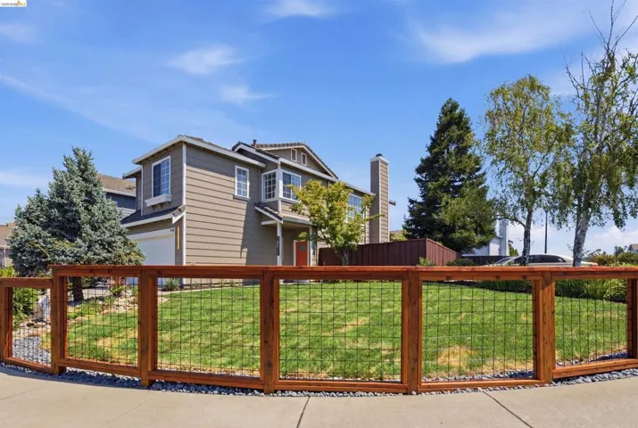 Front yard featuring a wood and wire panel fence, manicured lawn, and decorative gravel border