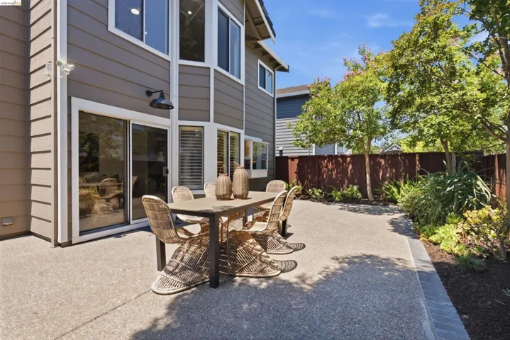 Spacious concrete patio with surrounding landscaped beds and privacy fencing