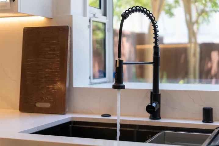 Matte black pull-down faucet over a deep black sink, set within a light countertop with subtle veining
