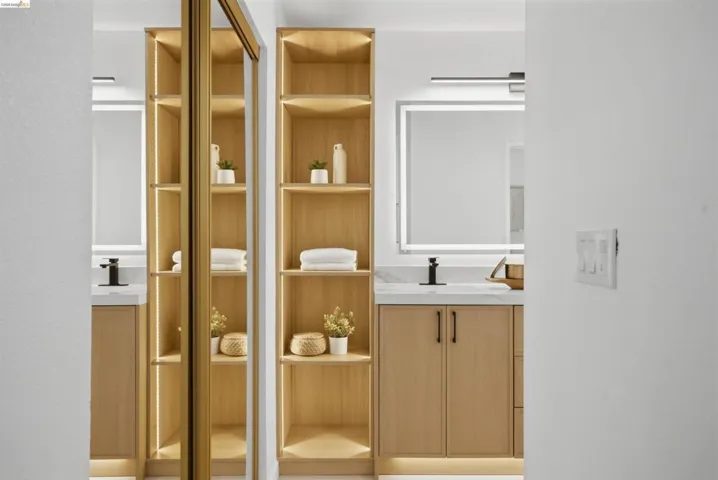 Bathroom vanity featuring light wood-finish cabinetry, a white countertop, and a rectangular illuminated mirror