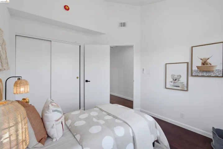 Wood-finish flooring with white baseboards, a white door with black hardware, and a white sliding closet door