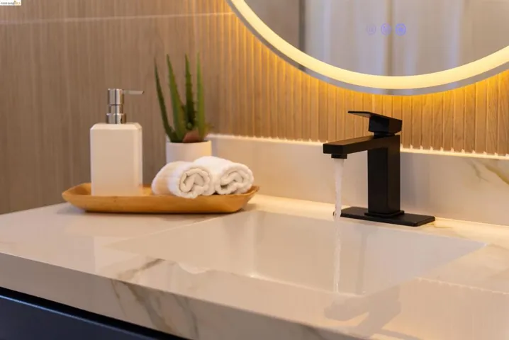 Modern bathroom vanity featuring a rectangular undermount sink, a matte black faucet, and a stone-finish countertop with subtle veining