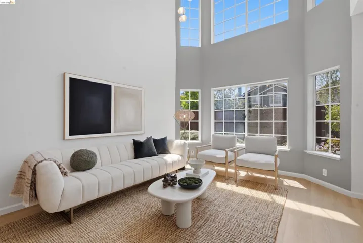 Double-height living space featuring expansive windows, light wood-finish flooring, and a neutral color palette