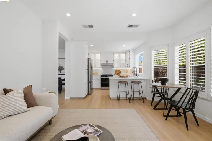 Open-concept living area featuring light wood-finish flooring, recessed lighting, and white plantation shutters