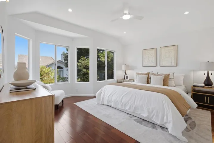 Bright bedroom featuring wood-finish flooring, a contemporary ceiling fan, recessed lighting, a vaulted ceiling, and multiple large windows