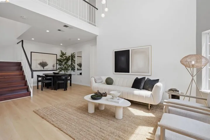 Two-story living area featuring light wood-finish flooring and a white color palette