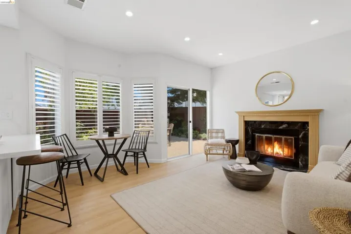 Warm living area featuring a fireplace with a black stone surround and a light wood mantle