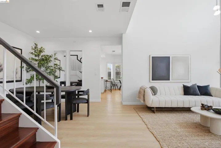 Vaulted ceiling in the main living area with recessed lighting, light wood-finish flooring, and a dark wood staircase with white risers