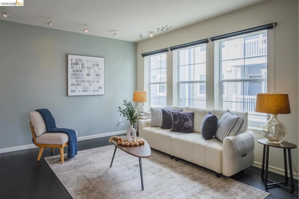 Spacious living area featuring dark wood-finish flooring, light blue and white painted walls, and track lighting