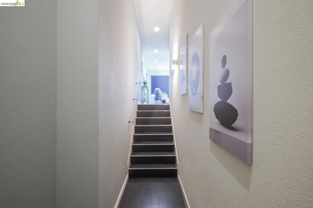 Staircase featuring dark wood-finish treads and flooring, recessed lighting, and a minimalist handrail